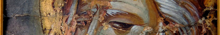 A peeling fresco of a saint. Only the eyes are visible