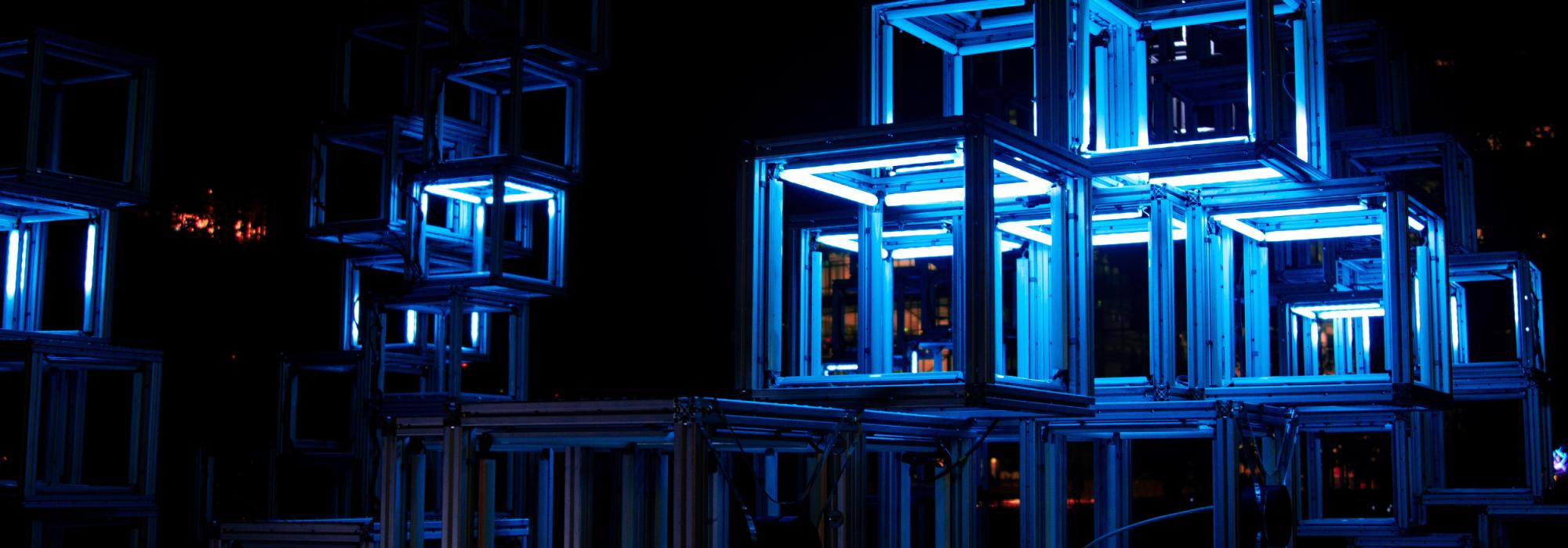 A series of lit up bokes that are implied to either be art or storage spaces for art