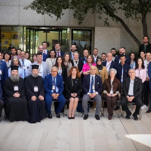 Group of conference attendees sitting formally in front of a building.